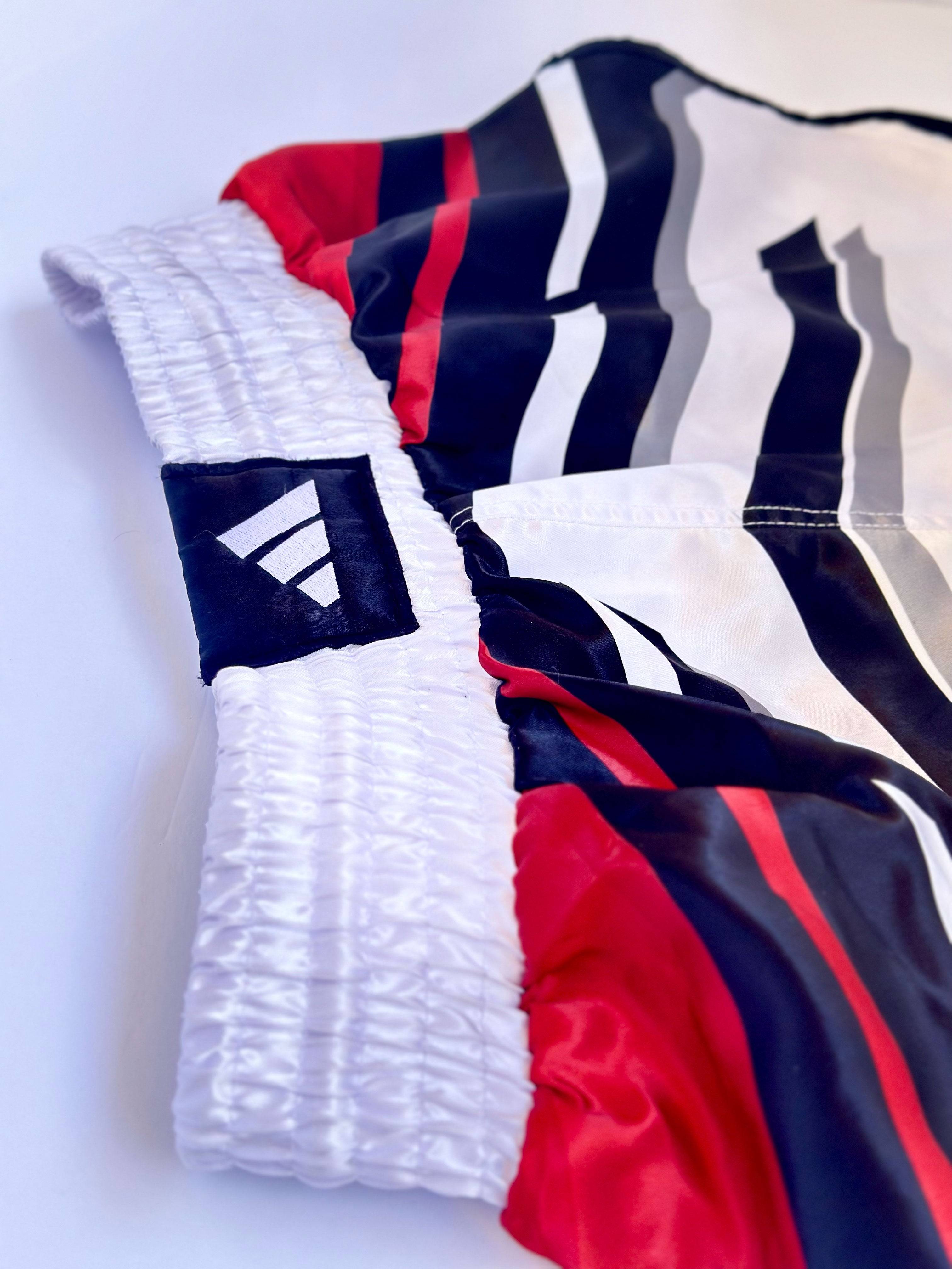 Close-up of ADIDAS Kickboxing Shorts waistband showing elastic fit and bold stripe pattern for high-performance combat sports wear.